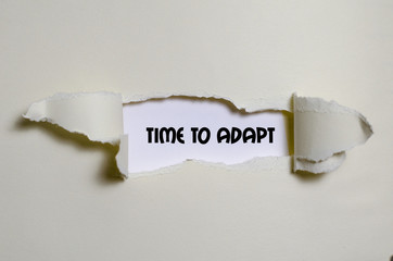The word time to adapt appearing behind torn paper