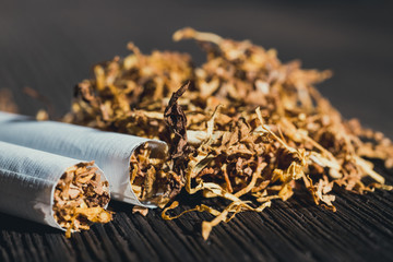homemade cigarettes and tobacco on the brown wooden table, close up with copy space