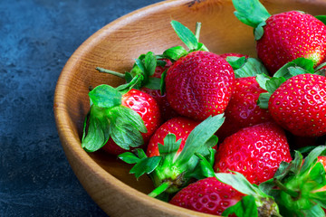 Full wooden bowl of ripe strawberries garden