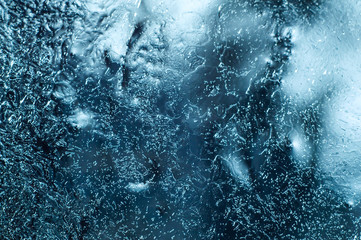 Frozen window with icy textured pattern, glass surface cracked ice macro view, soft focus shallow...