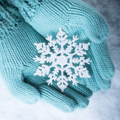 Female hands in light teal knitted mittens with sparkling wonder