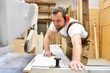 Tischler sägt Holzbrett in einer Schreinerei // Carpenter sawing wooden board in a carpenter's...