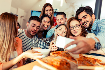 Group of young friends eating pizza and making selfie with smart phone.Party.