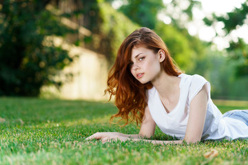 woman in a light t-shirt and in shorts lies on the grass, rest