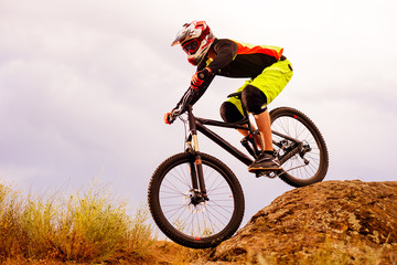 Naklejka premium Professional Cyclist Riding the Bike Down Rocky Hill. Extreme Sport Concept. Space for Text.