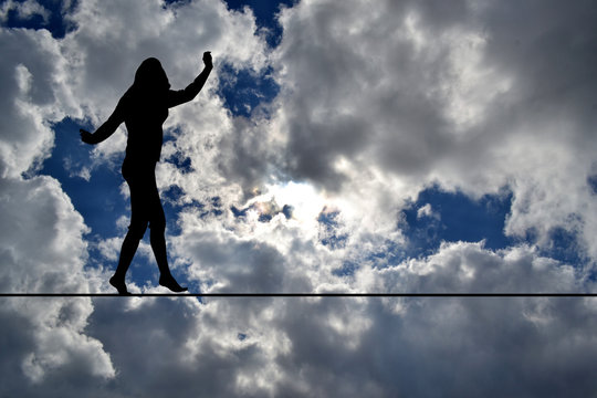 Woman silhouette balancing on rope