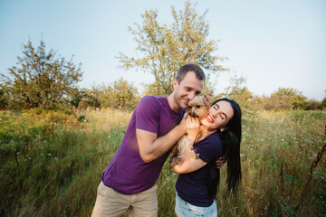 Young happy couple posing with their dog - yorkshire terrier on nature,love,lifestyle,relationship