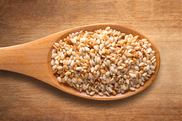Susame in wooden spoon on wooden background.