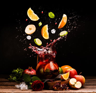 Sangria. Flying fruits. Apple, orange, lime, pomegranate, mint. Drink. Wine. Concept. Dark moody. Spain. Beverage jug. Juice jar.