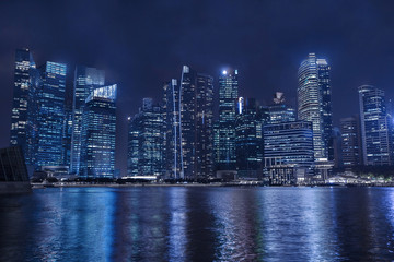 modern city skyline by night, business skyscrapers, office buildings with reflection in water