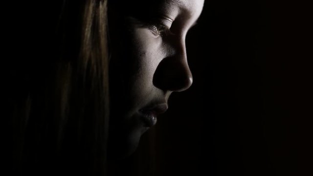 7Closeup portrait of a depressed teen girl in the dark. 4K UHD.