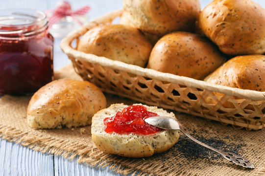 Homemade bread buns with poppy seeds and strawberry jam.