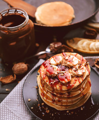 Pancake with chocolate and nut paste, walnuts and banana on a black plate