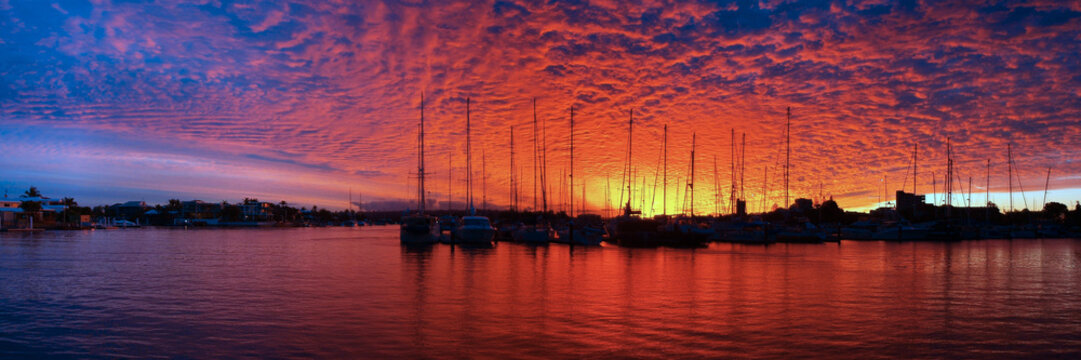 Crimson and Blue marina Sunset with water reflections and boats in silhouette.
Photo was taken at Mooloolaba, Queensland, Australia.
