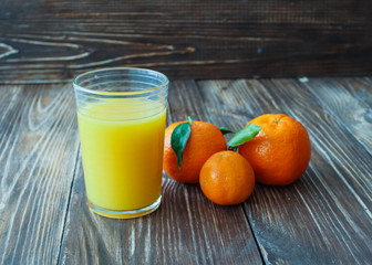 Fresh juice from tangerines with leaves on wooden table