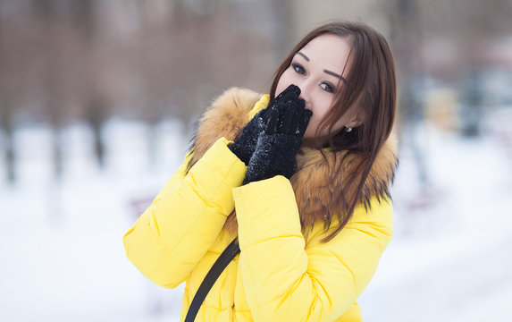 Portrait of young woman near fir-tree in winter. Female portrait. Woman in yellow winter coat.