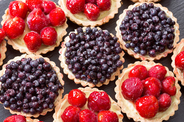 Fruit dessert tarts with strawberry and blueberry on wooden tabl