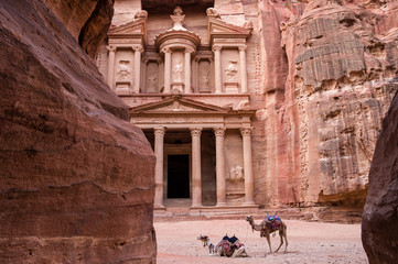 Ancient nabataean temple Al Khazneh (Treasury) located at Rose city - Petra, Jordan. Two camels infront of entrance. View from Siq canyon.