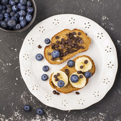 Healthy breakfast or snack. Two toast cereal bread with banana, blueberries and chocolate drops. Top view. Flat
