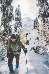Man Traveler with backpack hiking in winter forest landscape Travel Lifestyle concept adventure...