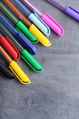 Colored pens on a grey wooden table