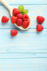 Red raspberries in spoon on a blue wooden table