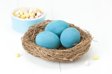 Painted Blue Easter Chicken Eggs In Bird Nest. Chocolate Eggs.