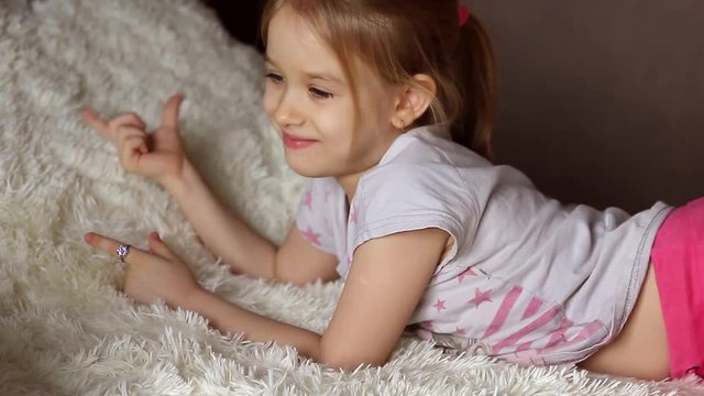 Cute little kid listening music lying on bed at home
