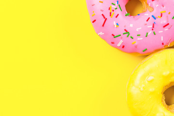 Pink round donut and few other on yellow background. Flat lay, top view.