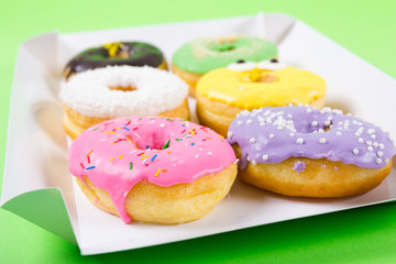 Strawberry, chocklate and other donuts in paper box on blue background