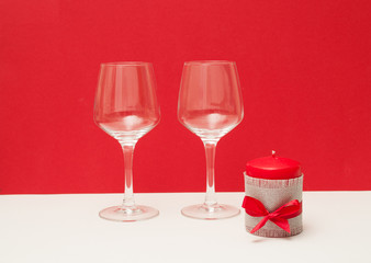 Two glasses of wine and a candle on a red background. Celebrate Valentine's Day