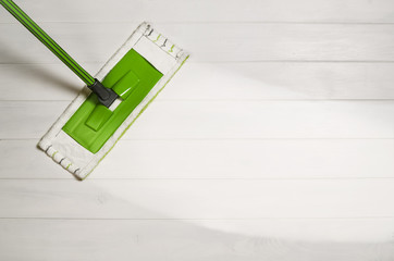 Cleaning floor with mop top view. Microfiber mop isolated on white wooden floor background. Home...