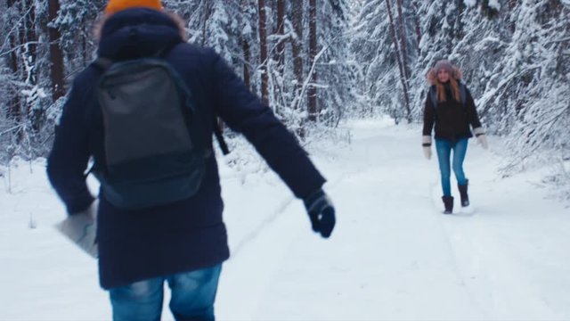HANDHELD Friends hiking together in winter forest, walking away from camera into the woods. 4K UHD, 60 FPS SLO MO, RAW edited footage