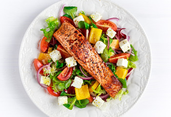 Fried Salmon steak with fresh vegetables salad, feta cheese. concept healthy food.