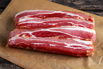 Raw smoked streaky sliced bacon on crumpled paper
