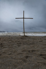 Handmade cross from rods on a stormy beach
