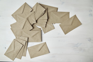 Heap of kraft paper brown envelopes on white wooden table