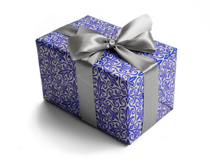 Small gift box wrapped with patterned blue paper and tied with gray ribbon with a bow. Isolated on white background.
