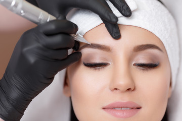 Permanent makeup. Tattooing of eyebrows - obrazy, fototapety, plakaty