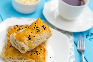 Homemade cheese puff pastries and cup of tea on blue wooden background