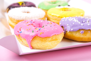 Strawberry, chocklate and other donuts in paper box on pink background