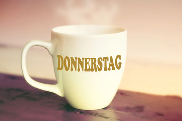 closeup of white cup with the german word Thursday