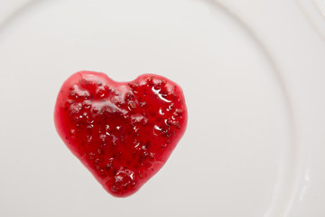 Obraz na płótnie Canvas Raspberries jam in the shape of heart isolated on white background.