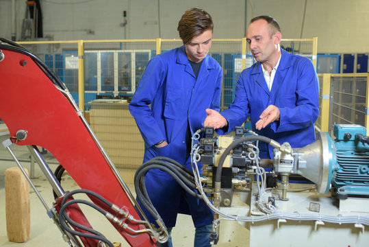 Engineers Looking At Hydraulic Arm Mechanicsm