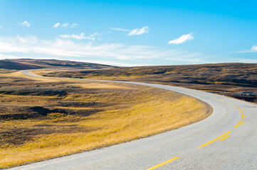 Empty asphalt windy road with yellow road markings and blue sky