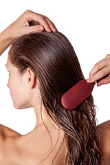 Young beautiful woman with white towel and freckles combing her brown wet hair after showering....