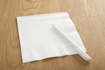 Blank White Napkin or Serviette and Pen on Wooden Surface