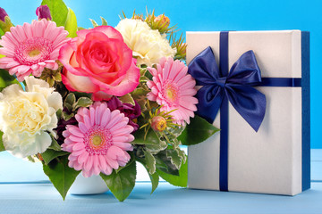 Blue gift box with beautiful bouquet of flowers