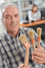 Decorator holding paint brushes