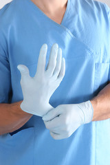 Doctor putting on sterile gloves isolated white
